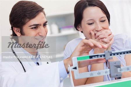 Young doctor adjusting scale for excited patient