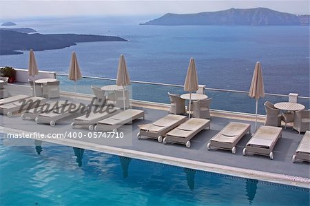 Row of pool chairs and umbrellas. Luxury hotel with caldera view at Santorini, Greece