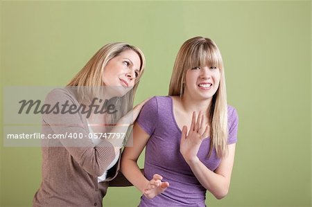 Caucasian mom with annoyed daughter over green background