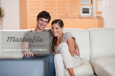 Jeune couple sur le canapé à regarder un film ensemble