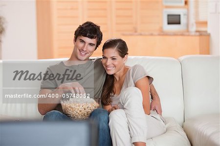 Young couple with popcorn on the sofa watching a movie