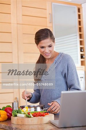 Young woman reading off a recipe while cooking