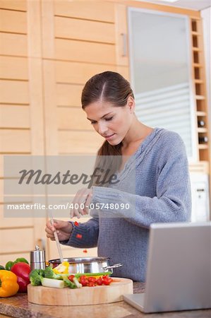 Young woman adding carrot pieces to her stew