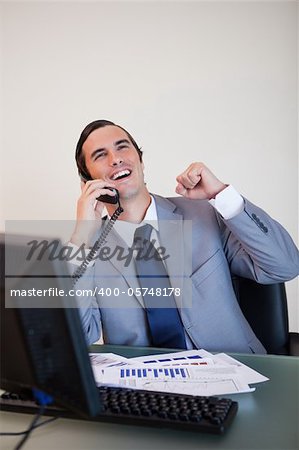 Cheerful businessman on the phone raising hand
