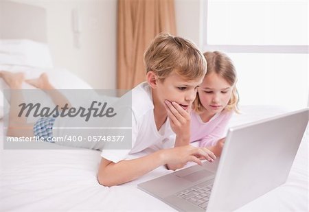 Children using a laptop in a bedroom