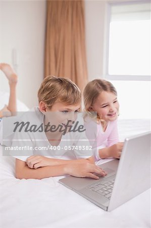 Portrait of children using a notebook in a bedroom
