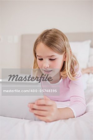 Portrait of a little girl using a tablet computer in a bedroom