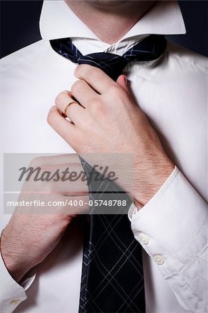 Businessman in a shirt doing his checkered tie