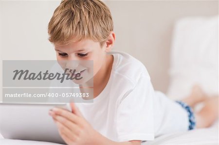 Smiling boy using a tablet computer in a bedroom