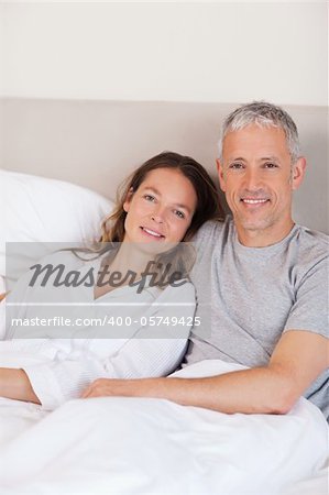 Portrait of a couple lying on a bed while looking at the camera