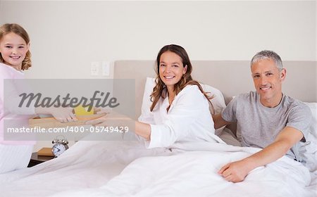 Young girl serving breakfast to her parents in their bedroom