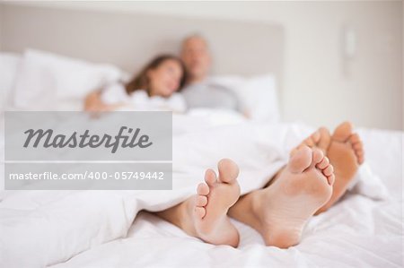 Lovely couple lying in a bed with the camera focus on their feed