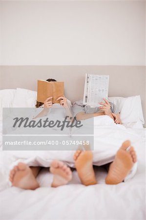 Portrait of playful couple reading in their bedroom