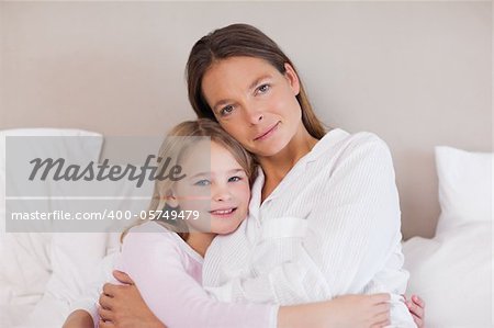 Mother and daughter hugging in a bedroom