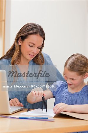 Portrait of a woman helping her daughter doing her homework in a kitchen