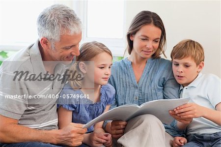 Family reading a book together in a living room