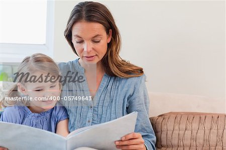Mother reading a book to her daughter in a living room