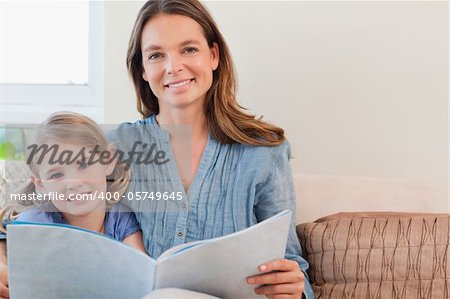 Happy mother reading a book to her daughter in a living room