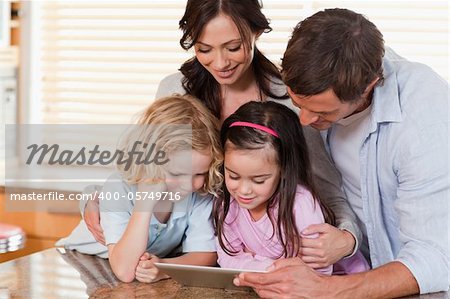 Happy family using a tablet computer together in a kitchen