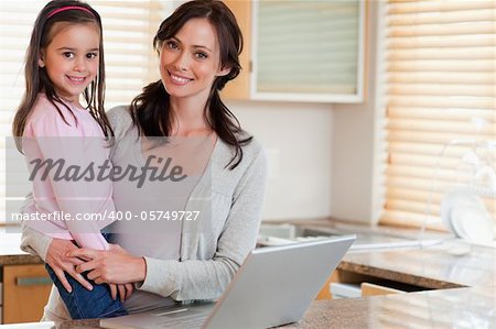 Girl and her mother using a notebook in a kitchen