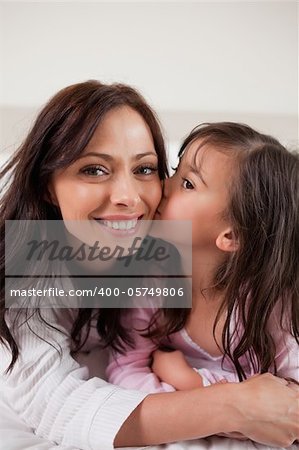 Portrait of a girl kissing her mother in a bedroom