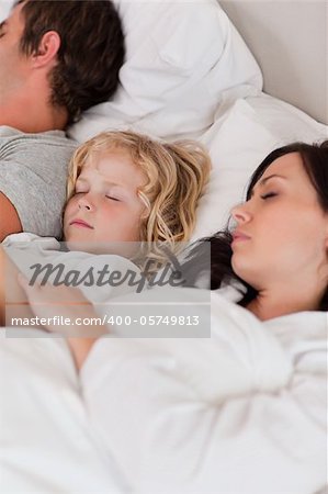 Portrait of a boy sleeping between his parents in a bedroom