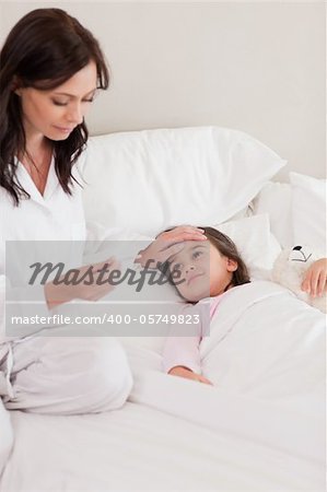 Portrait of a mother checking on her daughter's temperature in a bedroom