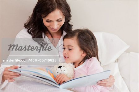 Mother reading a story to her daughter in a bedroom