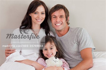 Parents posing with their daughter in a bedroom