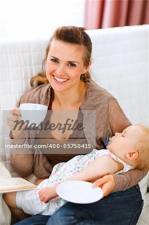 Happy mother resting while baby sleep by having tea and reading book