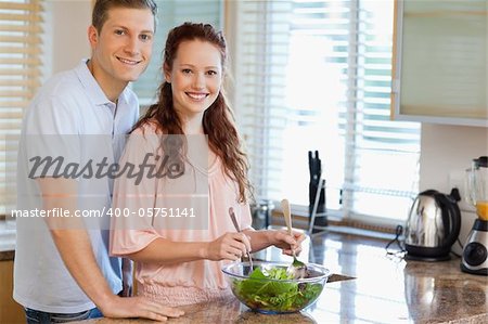 Young couple with salad in the kitchen