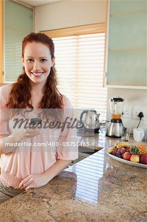Smiling woman in the kitchen with her cellphone
