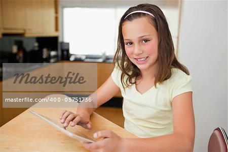 Girl with tablet sitting at the kitchen table