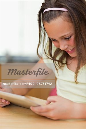 Girl sitting at the kitchen table while looking at tablet