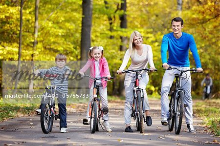 Family on bikes in the park in autumn
