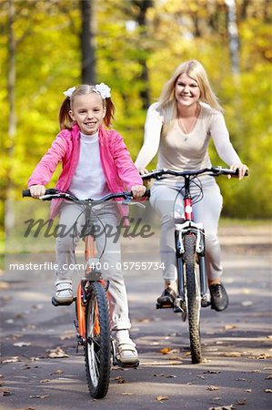 Mother and daughter on bicycle in autumn park