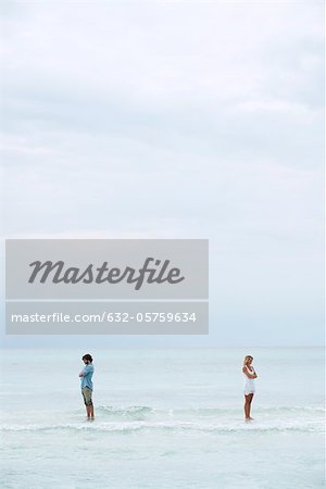 Couple standing apart in sea with backs turned toward each other