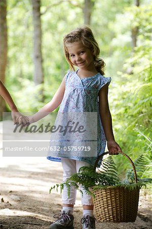 Girl carrying basket filled with fern fronds