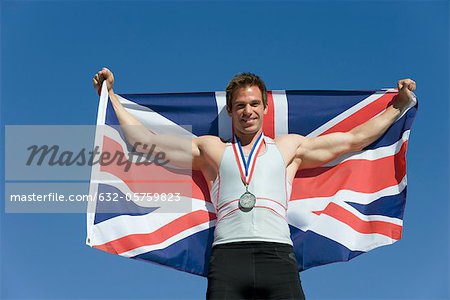 Männlicher athlet auf Podium des Siegers, halten britische Flagge