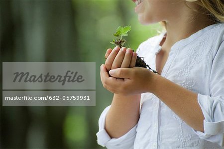 Girl holding seedling, cropped