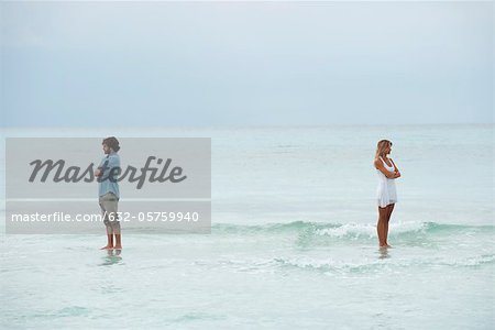 Couple standing apart in sea with backs turned toward each other