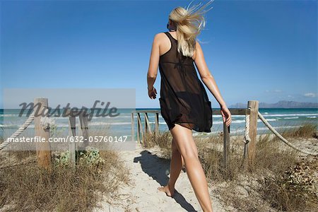 Femme qui marche sur le chemin de la plage vers la mer, vue arrière