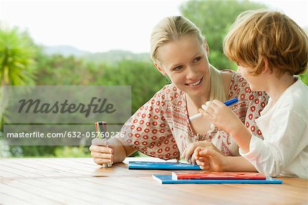 Mother and son sitting together with booklets and felt tip pens