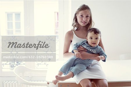 Girl holding baby sister on lap, portrait