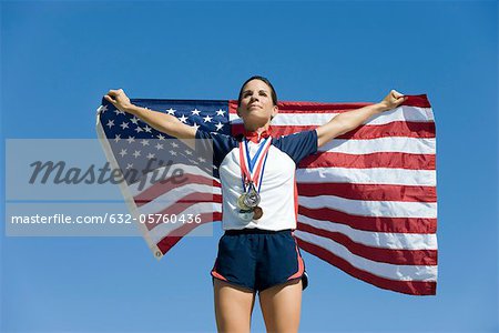 Athlète féminine étant honoré sur le podium, brandissant le drapeau américain