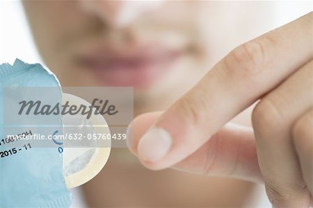 Man removing condom from wrapper, cropped