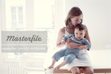 Girl kissing baby sister on lap, portrait