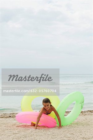 Girl playing with inflatable rings on beach