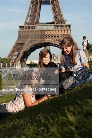France, Paris, Three young women on lawn in front of Eiffel Tower