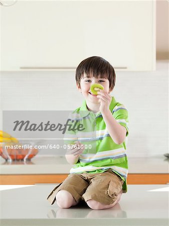 USA, Utah, Portrait of smiling boy (4-5) holding slice of kiwi